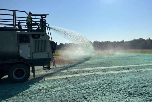a crew sprays a hydroseeding slurry over soil