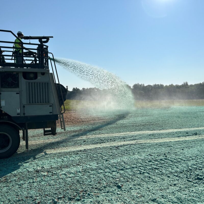 a crew sprays a hydroseeding slurry over soil